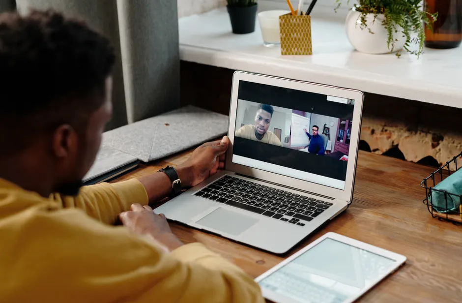 A man participates in an online video conference call from home using his laptop, fostering remote communication.