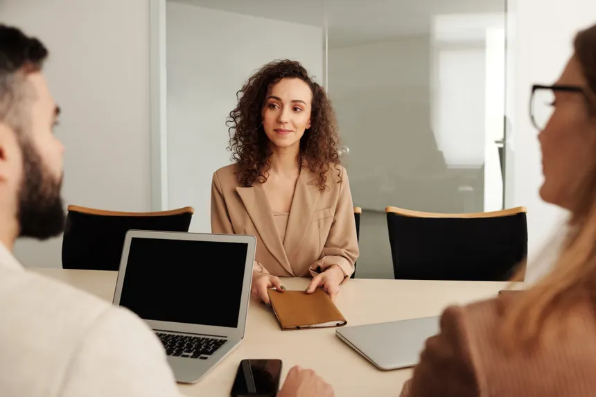 A woman in a business suit participates in a job interview, showcasing professionalism and modern office environment.