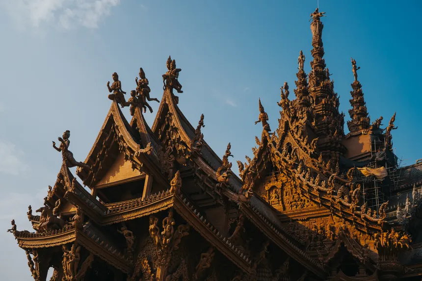 Wooden temple roof with detailed sculptures and carvings, capturing traditional Thai architecture in Bangkok.