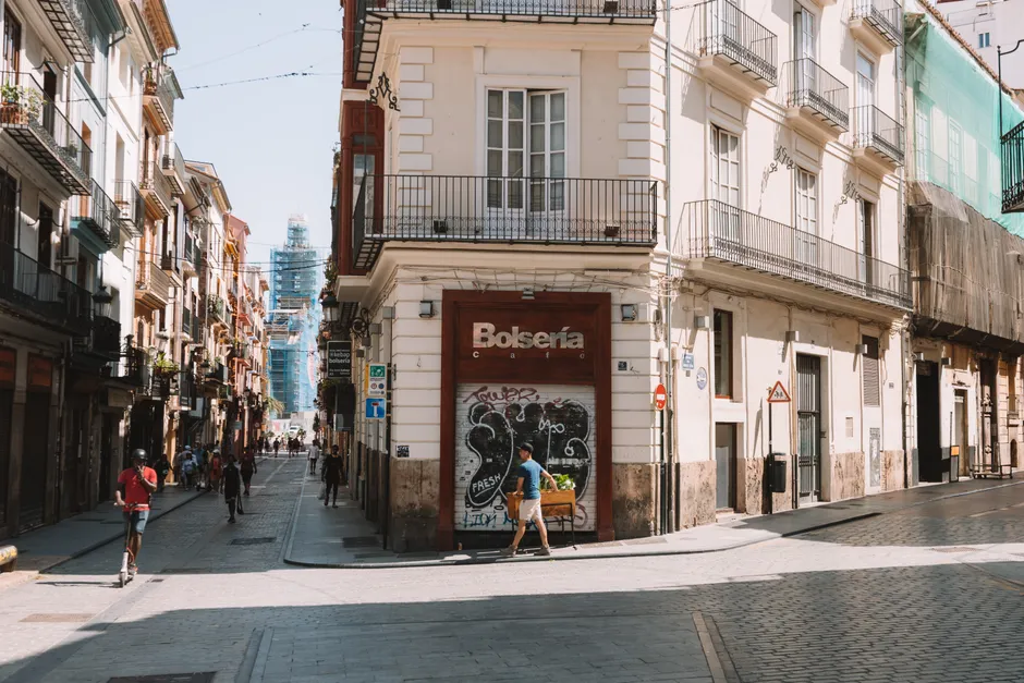 Sunlit urban street in Valencia, Spain, showcasing European architecture and city life.