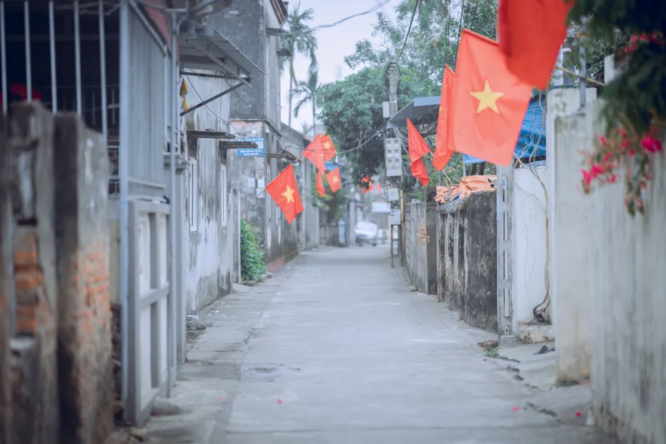 A tranquil street scene in Vietnam with national flags displayed along the path.