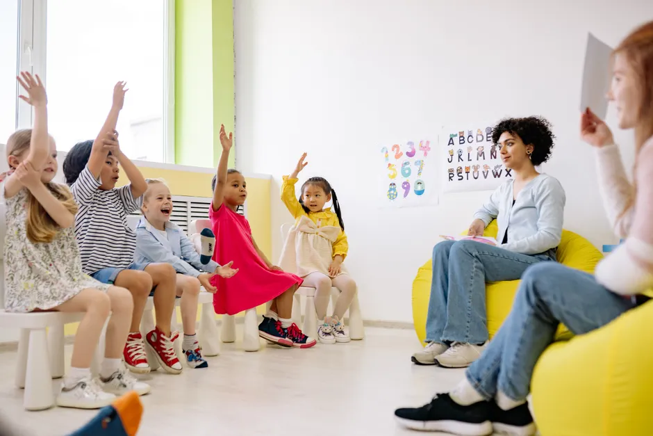 Children actively participate in a classroom with teachers, showcasing diversity and engagement.