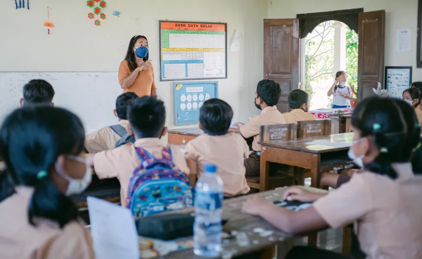 A classroom scene with students and a teacher wearing masks during a lesson.