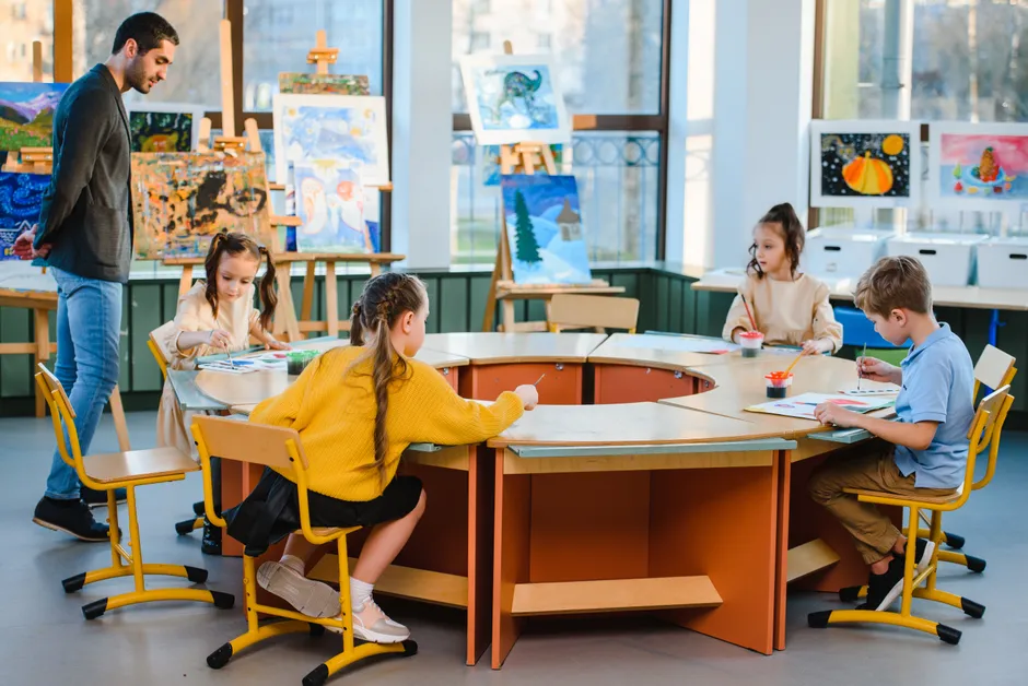 Young students participate in an art class, guided by their teacher in a creative indoor setting.