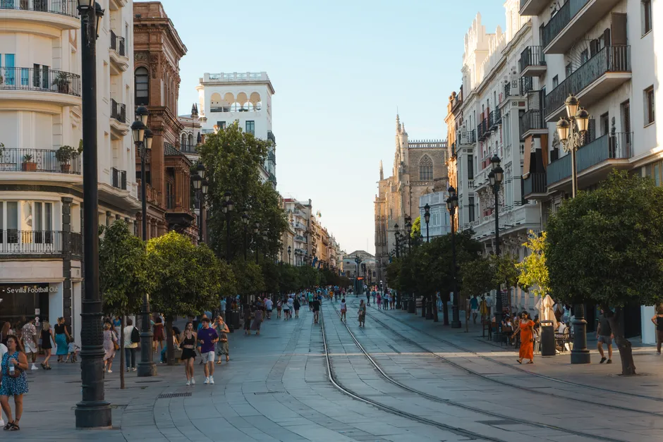 Vibrant day on a bustling street in Seville, showcasing the city's architecture and lively atmosphere.