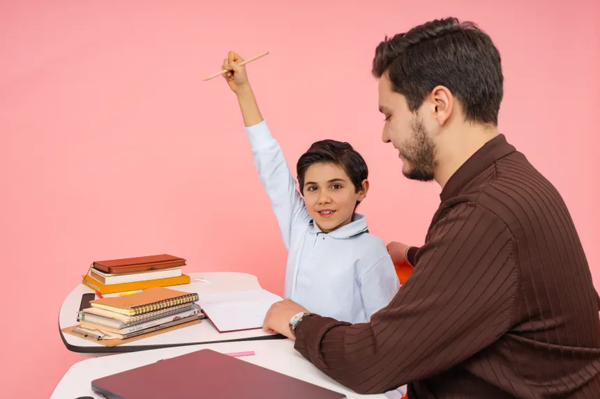 Teacher aids enthusiastic student in classroom setting, enhancing learning experience.