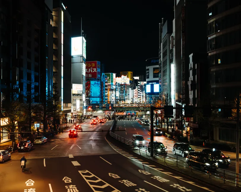 Explore the vibrant neon-lit streets of Tokyo at night, showcasing bustling urban energy.