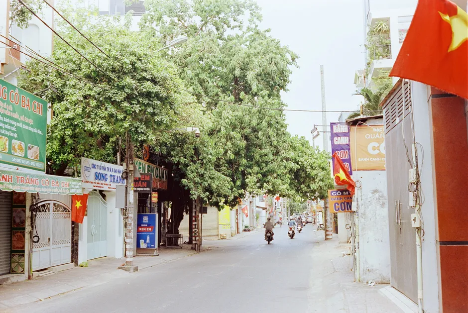 A vibrant street in Vietnam featuring scooters, trees, and local shops. Perfect urban summer scene.