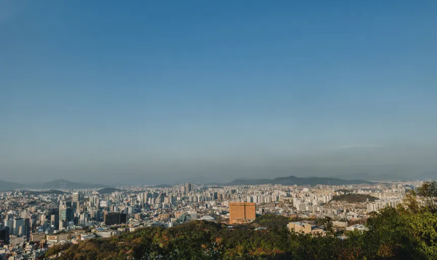 Expansive view of Seoul's skyline from a hilltop with clear blue sky.