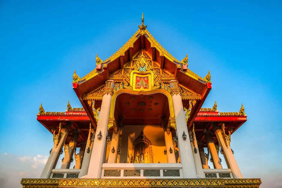 Stunning view of a traditional Thai temple with golden details under a bright blue sky.