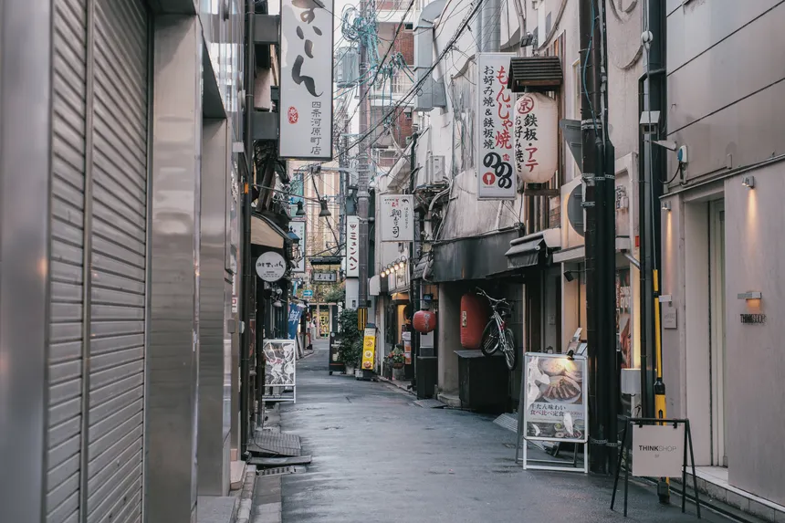 Capture of a quiet, narrow street in Tokyo, showcasing traditional Japanese architecture and vibrant signage.