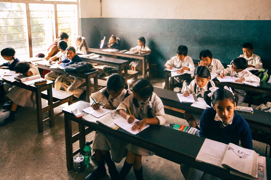 Elementary school children studying in a classroom, focusing intently on their work.