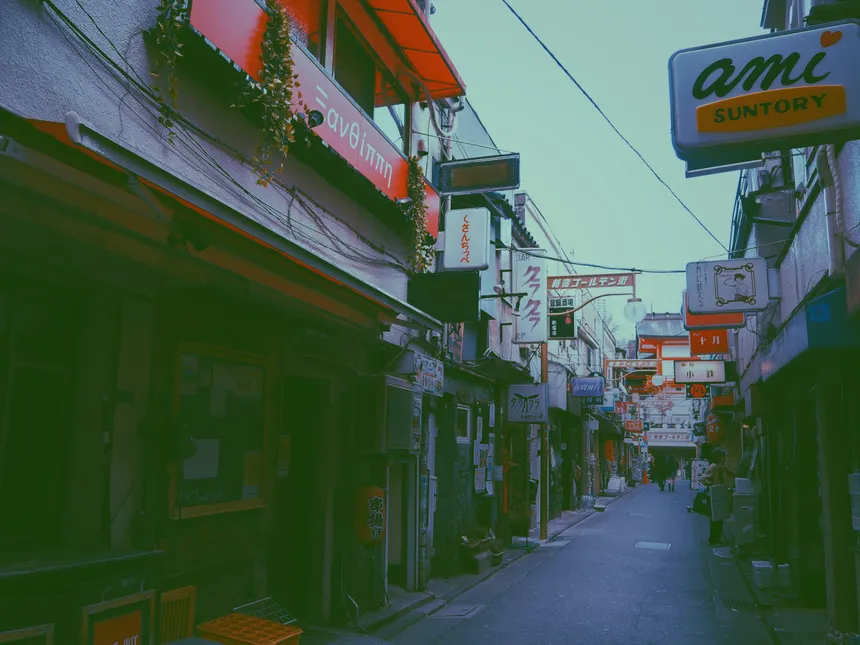 Explore a vibrant, narrow street lined with signs and traditional architecture under clear skies in Japan.